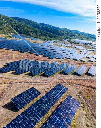 Solar panels cover a large field in a rural area under a clear blue sky during daytime Solar panels cover a large field in a rural area under a clear blue sky during daytime 143158852