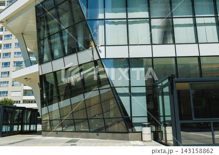 Modern building with large glass windows and unique angles in a city setting during the day 143158862