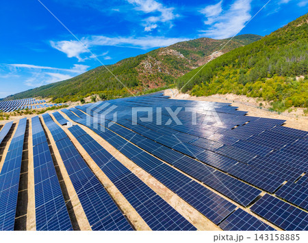 Solar panels cover a large area with blue sky and mountains in the background during daytime Solar panels cover a large area with blue sky and mountains in the background during daytime 143158885
