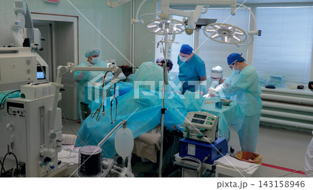 Surgical team performing operation in modern hospital room with sterile gowns and bright lights 143158946