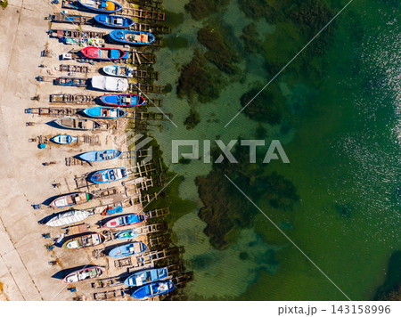 Boats lined up at a harbor with clear water in view during the day Boats lined up at a harbor with clear water in view during the day 143158996