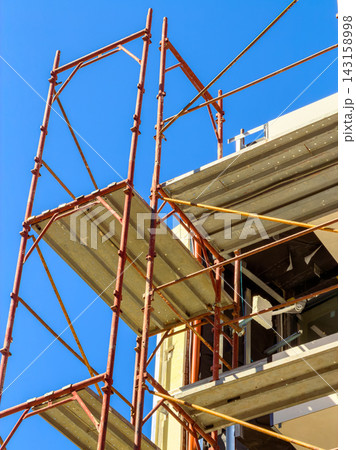 Construction work is happening with scaffolding set up against a bright blue sky Construction work is happening with scaffolding set up against a bright blue sky 143158998