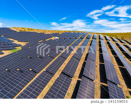 Rows of solar panels on a sunny day in a field on a hillside with blue sky and clouds Rows of solar panels on a sunny day in a field on a hillside with blue sky and clouds 143159053