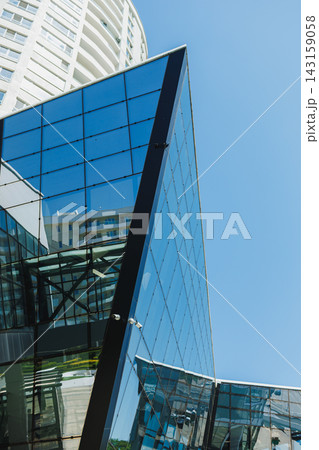 Modern building with glass facade reflecting blue sky in urban setting 143159058