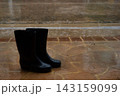 Black Rubber Rain Boots on Wet Patio During Heavy Rain 143159099