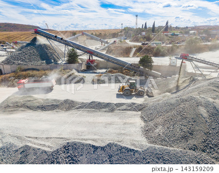 Granite quarry process with trucks and machinery working on site during the day 143159209