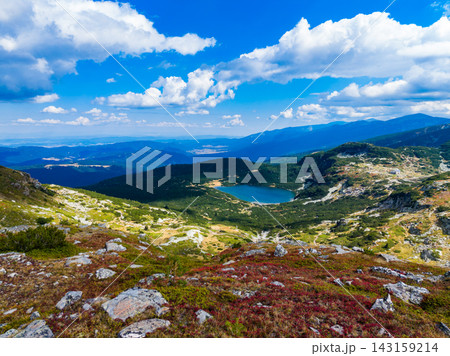 Mountain view showing a lake in the valley under a blue sky with clouds in Bulgaria during summer 143159214