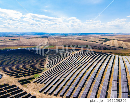 Solar panel field in an open area with blue sky and clouds during the day in a rural location 143159293