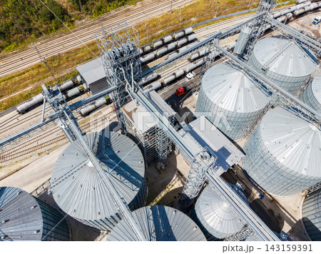 Large grain storage facility with silos and rail cars in a rural area during daylight Large grain storage facility with silos and rail cars in a rural area during daylight 143159391