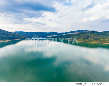 Scenic view of a lake surrounded by mountains under a cloudy sky in a remote area during daylight hours 143159460