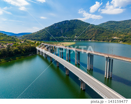 Bridge spans over water with hills in the background under a clear sky during the day 143159477