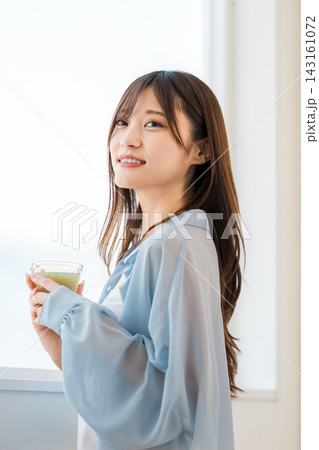 朝食にグリーンスムージーを飲む若い女性。栄養と健康を意識した朝の習慣 朝食にグリーンスムージーを飲む若い女性。栄養と健康を意識した朝の習慣 143161072