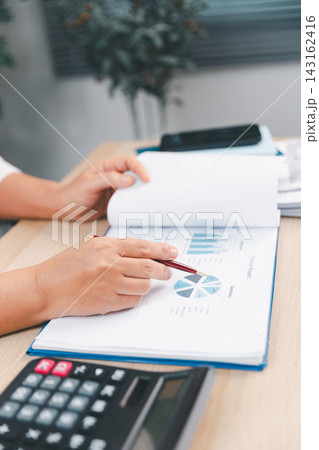 Business professional pointing at pie charts in a financial report with a pen, representing accounting, budget allocation, statistics, market analysis, performance review, planning, Business professional pointing at pie charts in a financial report with a pen, representing accounting, budget allocation, statistics, market analysis, performance review, planning, 143162416
