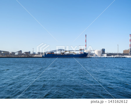 Cargo ship loading steel products at a port near a heavy industrial metallurgical plant. 143162612