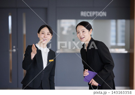 受付で訪問者を案内する女性スタッフ 受付で訪問者を案内する女性スタッフ 143163358