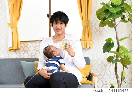おもちゃで赤ちゃんをあやす笑顔の若い父親 143163428
