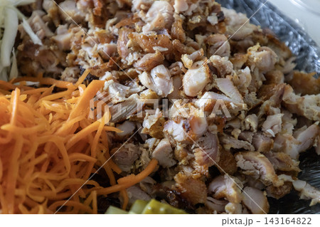 Ingredients for homemade shawarma or kebab on a plate: chopped chicken meat, shredded white cabbage, fresh grated carrots, and sliced pickles ready for cooking wrap. 143164822