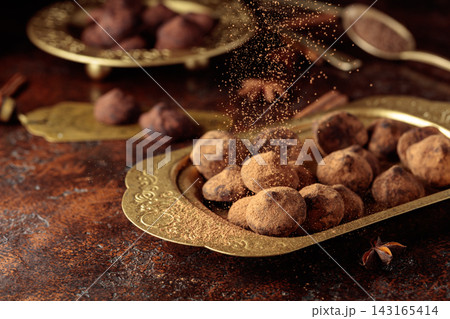 Chocolate truffles in old brass dish are sprinkled with cocoa powder. Chocolate truffles in old brass dish are sprinkled with cocoa powder. 143165414