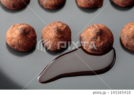 Chocolate truffles and chocolate sauce on a black plate. Chocolate truffles and chocolate sauce on a black plate. 143165418