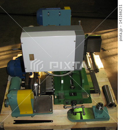 Top view of an industrial machine tool assembly with a central control unit, green metal base, electric motor, and components mounted on a wooden shipping pallet. Top view of an industrial machine tool assembly with a central control unit, green metal base, electric motor, and components mounted on a wooden shipping pallet. 143166251