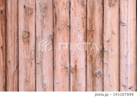 Weathered wooden surface presenting a rustic pattern of vertical timber planks and visible knots, providing a natural background with a warm color 143167899