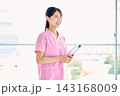 窓辺でクリップボードを持って微笑む看護師 窓辺でクリップボードを持って微笑む看護師 143168009
