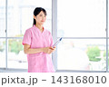 窓辺に立つピンクのスクラブの看護師 窓辺に立つピンクのスクラブの看護師 143168010