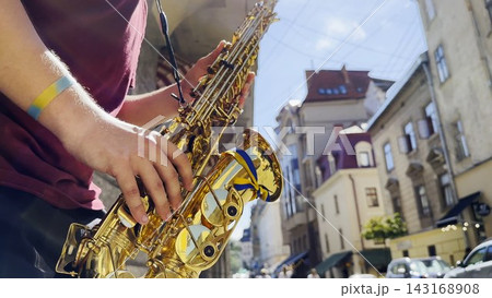 Male fingers of musician play the saxophone on summer day. Natural light reflects off metal surface, highlighting movement and rhythm. Scene captures live urban music and atmosphere street performance 143168908