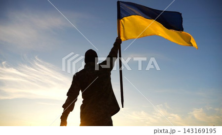 Silhouette of male military lifting blue-yellow banner in honor of the victory against russian aggression at sunset. Soldier of ukrainian army raised a waving flag of Ukraine at countryside. Slow mo Silhouette of male military lifting blue-yellow banner in honor of the victory against russian aggression at sunset. Soldier of ukrainian army raised a waving flag of Ukraine at countryside. Slow mo 143169195