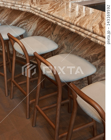 bar stools arranged in a row on a marble countertop in an elegant indoor setting with a top-down perspective, possibly a bar or restaurant interior design space. 143169592