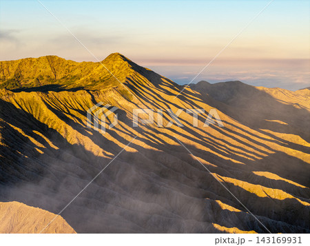 Golden light carves sharp shadows across rugged mountain ridges 143169931