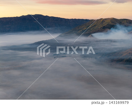 Misty dawn blankets rolling hills in soft, hazy embrace 143169979
