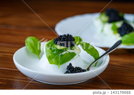 Gourmet egg with black caviar on rustic wooden background Gourmet egg with black caviar on rustic wooden background 143170088