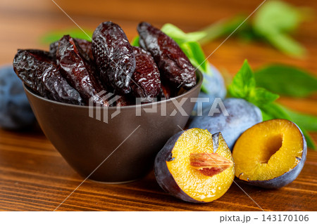 Homemade dried plums in bowl on rustic wooden background 143170106