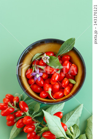 Fresh goji berries and flowers arranged on green background Fresh goji berries and flowers arranged on green background 143170121