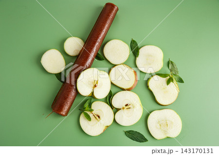 Natural apple fruit leather rolls with mint on green background Natural apple fruit leather rolls with mint on green background 143170131