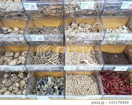 Assorted dried herbs and spices displayed in transparent acrylic storage bins. 143170948