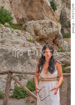 Young Chinese woman posing in front of the rocks of the Neapolis Archaeological Park in Syracuse, Italy Young Chinese woman posing in front of the rocks of the Neapolis Archaeological Park in Syracuse, Italy 143171249