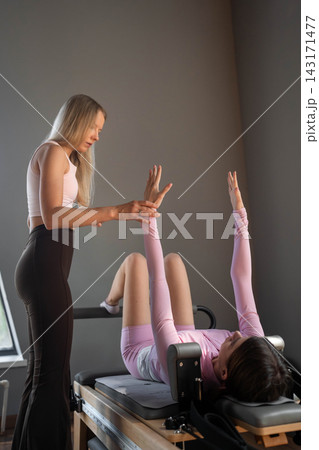 Woman exercises Glute bridge on a reformer bed machine in natural sunlight, focusing on pelvis and hips. Woman exercises Glute bridge on a reformer bed machine in natural sunlight, focusing on pelvis and hips. 143171477