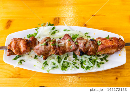 pork shashlik on steel skewer on plate on table 143172188