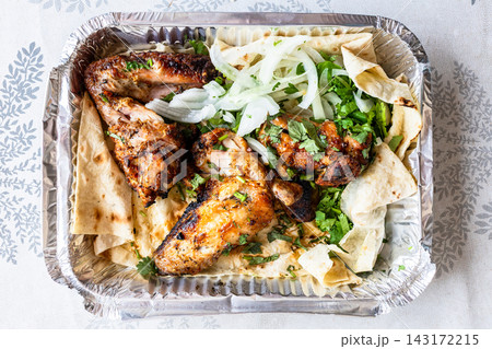 grilled chicken wings in foil container on table grilled chicken wings in foil container on table 143172215