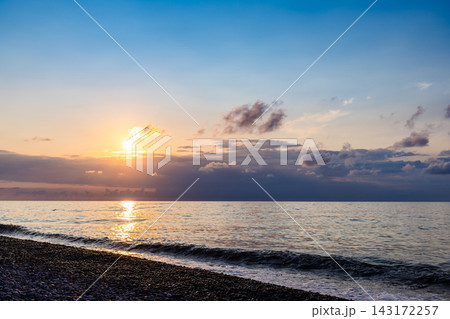 setting sun in dark blue sky over sea and beach 143172257