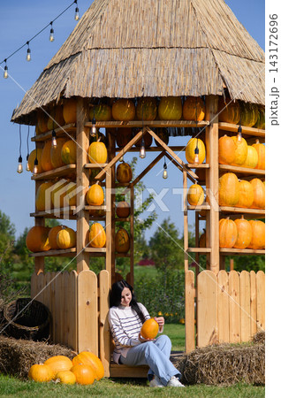 Woman holding pumpkin at outdoor pumpkin patch on sunny autumn day 143172696