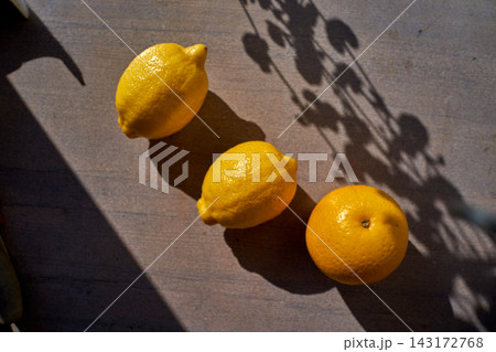 Three fresh lemons on gray stone pavement in strong sunlight with long shadows, close-up for cooking and lemonade 143172768
