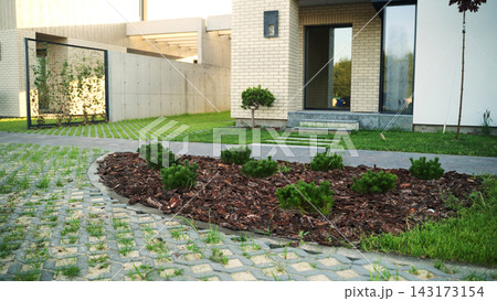 Contemporary house exterior with modern landscaping design, mulched garden bed, green lawn, and geometric grass permeable pavers 143173154