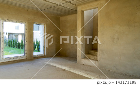 Unfinished room showing concrete walls, floor, and ceiling, with window frames installed, depicting a new housing development stage 143173199