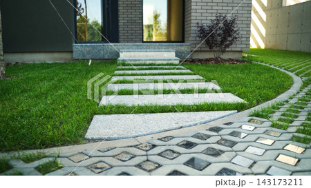 Contemporary house featuring a garden with a paved path, grass stepping stones, and eco-friendly permeable driveway 143173211