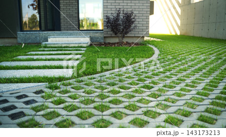 Exterior view of a contemporary house featuring a modern garden path with grass pavers and stone steps 143173213