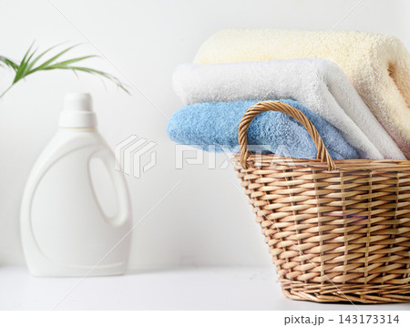 Stacked pastel towels in wicker basket beside laundry detergent bottle on white countertop linen set Stacked pastel towels in wicker basket beside laundry detergent bottle on white countertop linen set 143173314