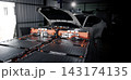 EV car service. Electric vehicle battery pack being serviced or inspected in automotive workshop. Large battery modules and high voltage components. Modern EV power systems. Lithium ion NMC NCA or LFP 143174135